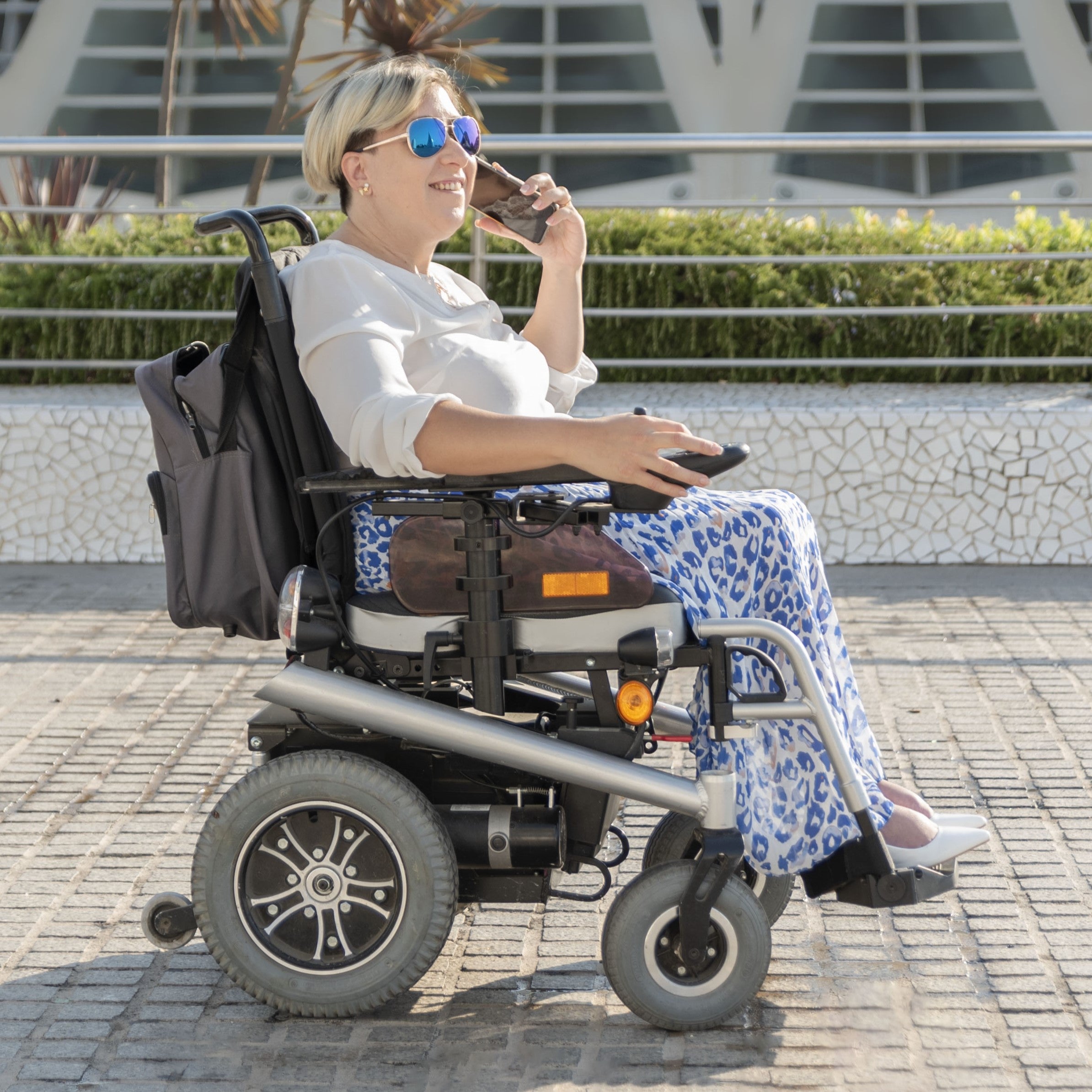 //bestmobilityequipment.com/cdn/shop/files/tourist-talking-smartphone-electric-wheelchair-city-street_1.jpg?v=1694620957